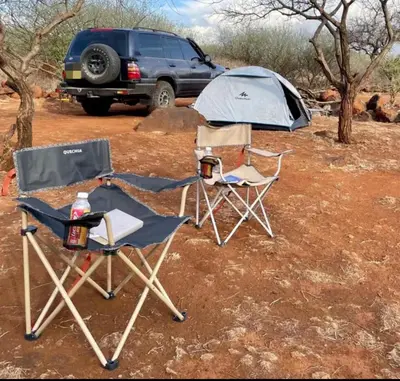 two camping chairs and a tent in a field at Mawe Hillside Campsite in Arusha