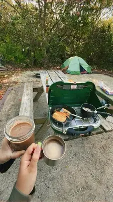 a person holding a cup of coffee at a picnic table at Mawe Hillside Campsite in Arusha