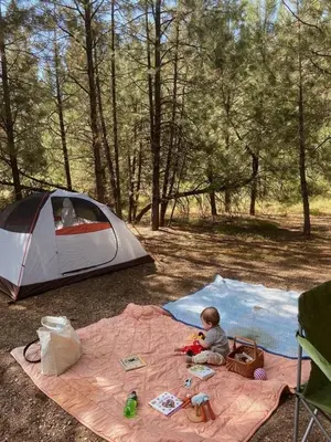 a baby sitting on a blanket in front of a tent at Mawe Hillside Campsite in Arusha
