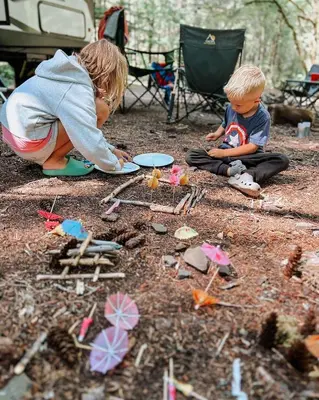a child and a boy playing with toys on the ground at Mawe Hillside Campsite in Arusha