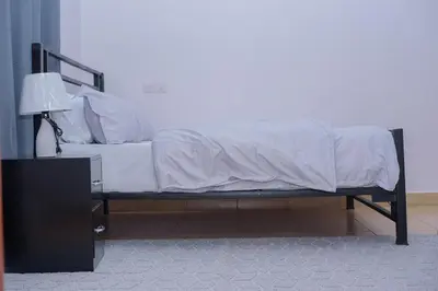 a bed with white sheets and a lamp in a room at Sonia homes shared in Arusha