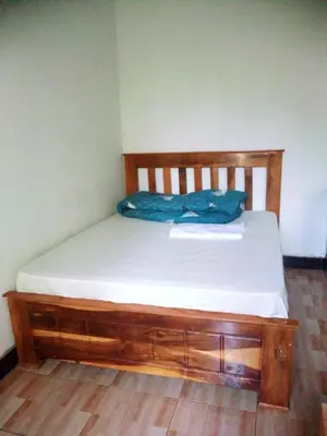 a bed in a room with a wooden bed frame at Banana Grove Retreat in Shiri