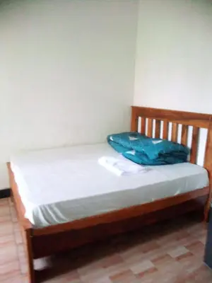 a wooden bed with a blue blanket on it at Banana Grove Retreat in Shiri