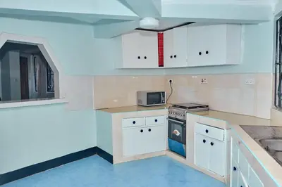 a kitchen with white cabinets and a stove top oven at Arusha Garden Home - Antique Villa in Arusha