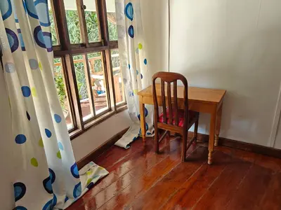 a room with a wooden table and a chair and a window at Arusha Garden Home - Antique Villa in Arusha