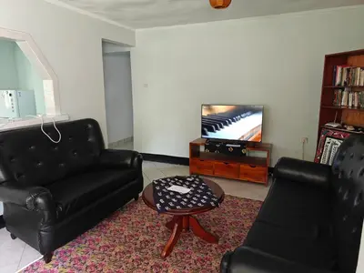 a living room with two black chairs and a television at Arusha Garden Home - Antique Villa in Arusha