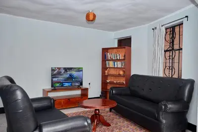a living room with a black leather couch and a table at Arusha Garden Home - Antique Villa in Arusha