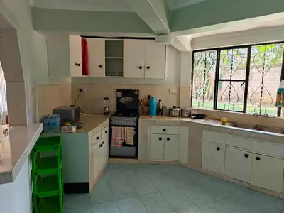 a kitchen with white cabinets and a large window at Arusha Garden Home - Antique Villa in Arusha