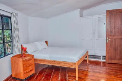 a bedroom with a bed and a dresser and a window at Arusha Garden Home - Antique Villa in Arusha