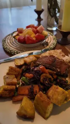 a plate of food with meat and vegetables on a table at Bomani House in Arusha