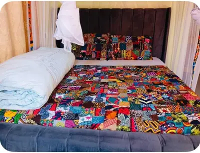 a bed with a colorful quilt on top of it at Tropical Garden Homestay in Arusha