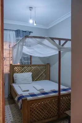 a bedroom with a wooden bed with a canopy at Seuri Bar and Guesthouse in Arusha
