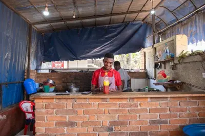 a boy standing at a counter in a kitchen at Seuri Bar and Guesthouse in Arusha