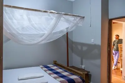 a man is walking into a bedroom with a bed at Seuri Bar and Guesthouse in Arusha