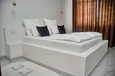 a white bed with two pillows on top of it at Smile Apartments Arusha in Arusha