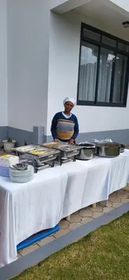 a man standing behind a table with food on it at Smile Apartments Arusha in Arusha