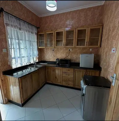 a kitchen with wooden cabinets and a sink and a refrigerator at MD Apartments in Arusha