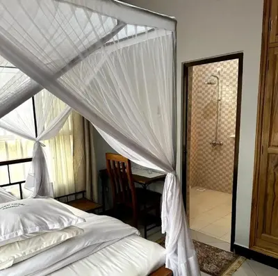 a bedroom with a canopy bed and a shower at MD Apartments in Arusha