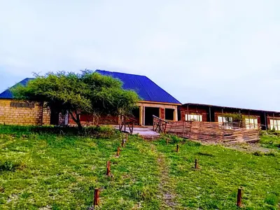 a barn in a field next to a building at Anapa Lodge and Camp in Mto wa Mbu