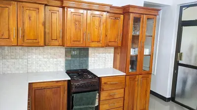 a kitchen with wooden cabinets and a stove at Mama Evaline Family Home in Boma la Ngombe