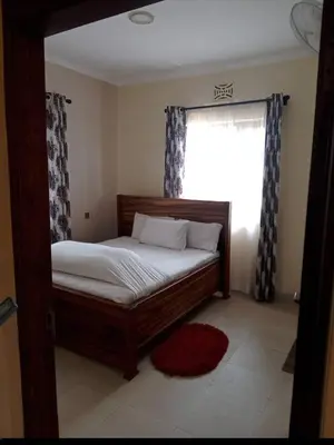 a bedroom with a wooden bed with a window at SEELA CLASSIC LODGE-Mbauda Arusha Tanzania in Arusha