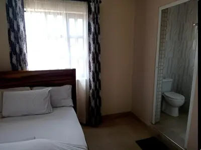 a bedroom with a bed and a window with a toilet at SEELA CLASSIC LODGE-Mbauda Arusha Tanzania in Arusha