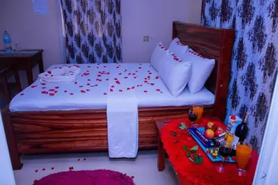a small bedroom with a bed with red confetti at SEELA CLASSIC LODGE-Mbauda Arusha Tanzania in Arusha