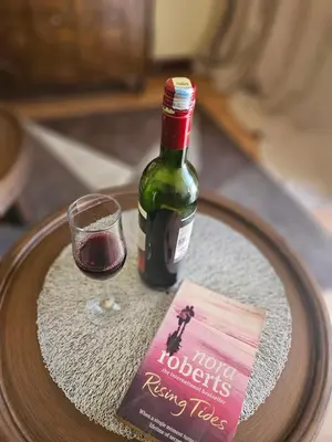 a bottle of wine and a book on a table at Elite Homes in Arusha