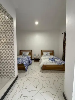 a bedroom with two beds and a tile floor at Mlangoni Cottages in Sanya Juu