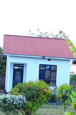 a small blue and white house with a red roof at Mlangoni Cottages in Sanya Juu