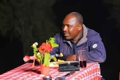 a man sitting at a table with a plate of food at Mlangoni Cottages in Sanya Juu