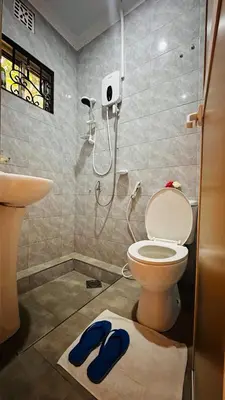 a bathroom with a toilet and a sink and blue slippers at Sanplay Homes in Arusha