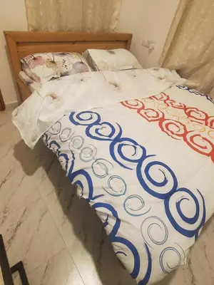 a bed with a blue and white blanket on it at Ma lo Lounge n Lodge