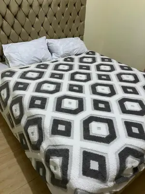 a bed with a black and white blanket on it at Friendly House in Arusha