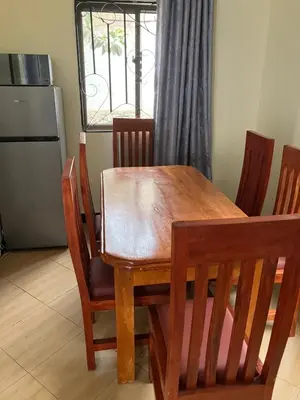 a wooden dining room table with chairs and a window at Friendly House in Arusha