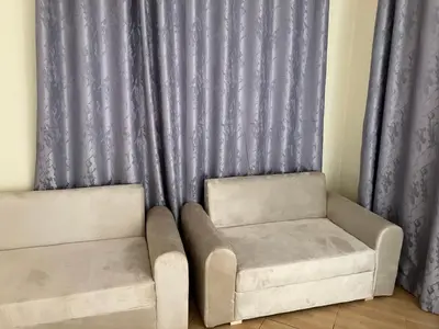 two chairs and a couch in front of a curtain at Friendly House in Arusha