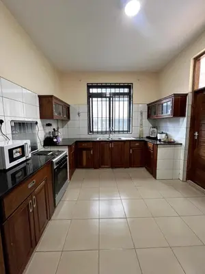 a large kitchen with wooden cabinets and a window at Apartment in Arusha City Centre AICC in Arusha