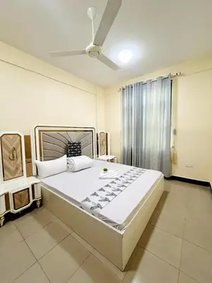 a bedroom with a large bed with a ceiling fan at Apartment in Arusha City Centre AICC in Arusha