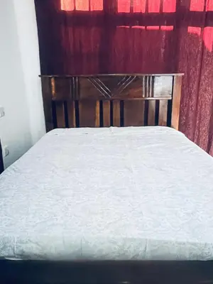 a bed with a wooden headboard and a red curtain at Osim Bnb in Arusha