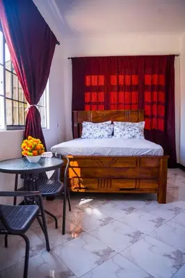 a bedroom with a wooden bed and a table with a table sidx sidx at Osim Bnb in Arusha