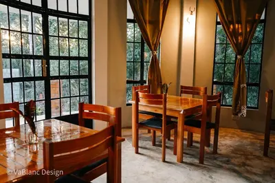 a dining room with a table and chairs and windows at Naishika Home Stay in Tengeru