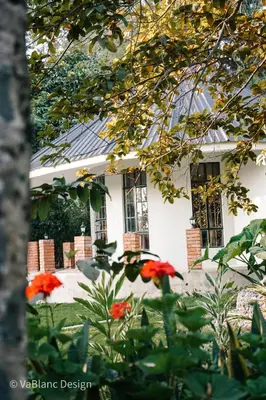 a white house with red flowers in front of it at Naishika Home Stay in Tengeru
