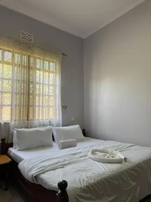 a bedroom with a large bed with white sheets and a window at Oasis HomeStay in Arusha