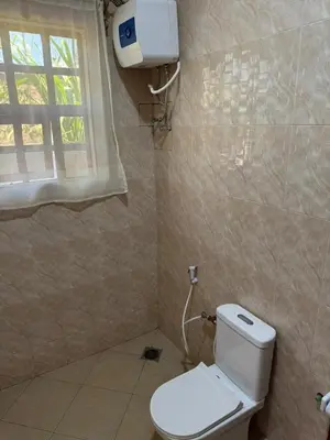 a bathroom with a white toilet and a window at Oasis HomeStay in Arusha