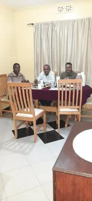 a group of three men sitting at a table at J&T Homestay in Karatu