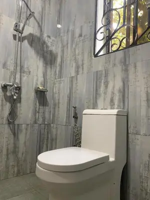 a bathroom with a white toilet and a window at Datogga Homestay in Kitumbeine