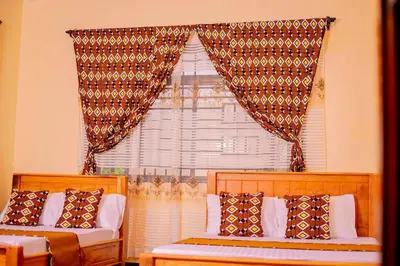 a bedroom with two beds and a window with curtains at Materuni Home Stay in Uru East