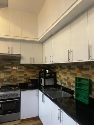 a kitchen with white cabinets and a black counter top at Lavish 2 Bedroom in Arusha