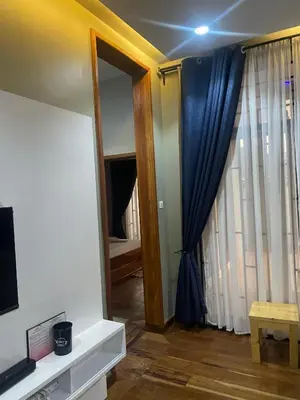 a living room with a tv and a window at Lavish 2 Bedroom in Arusha