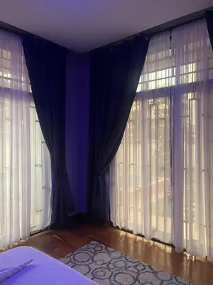a bedroom with two large windows with curtains at Lavish 2 Bedroom in Arusha